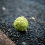 green tennis ball on the pavement