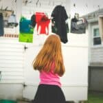 girl standing under clothes on airer at daytime