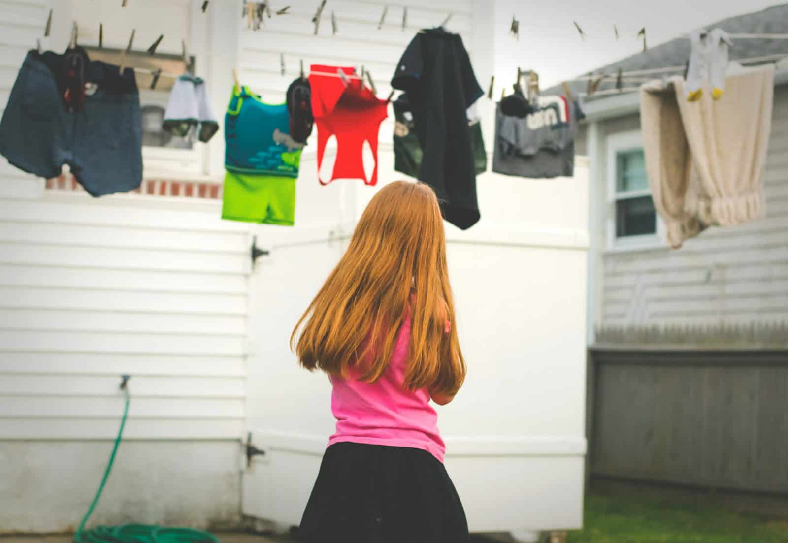 girl standing under clothes on airer at daytime