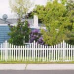 white wooden fence near green trees during daytime