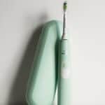 an electric toothbrush sitting on top of a green case