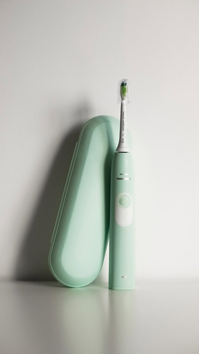 an electric toothbrush sitting on top of a green case