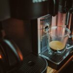 a glass of liquid on a coffee machine